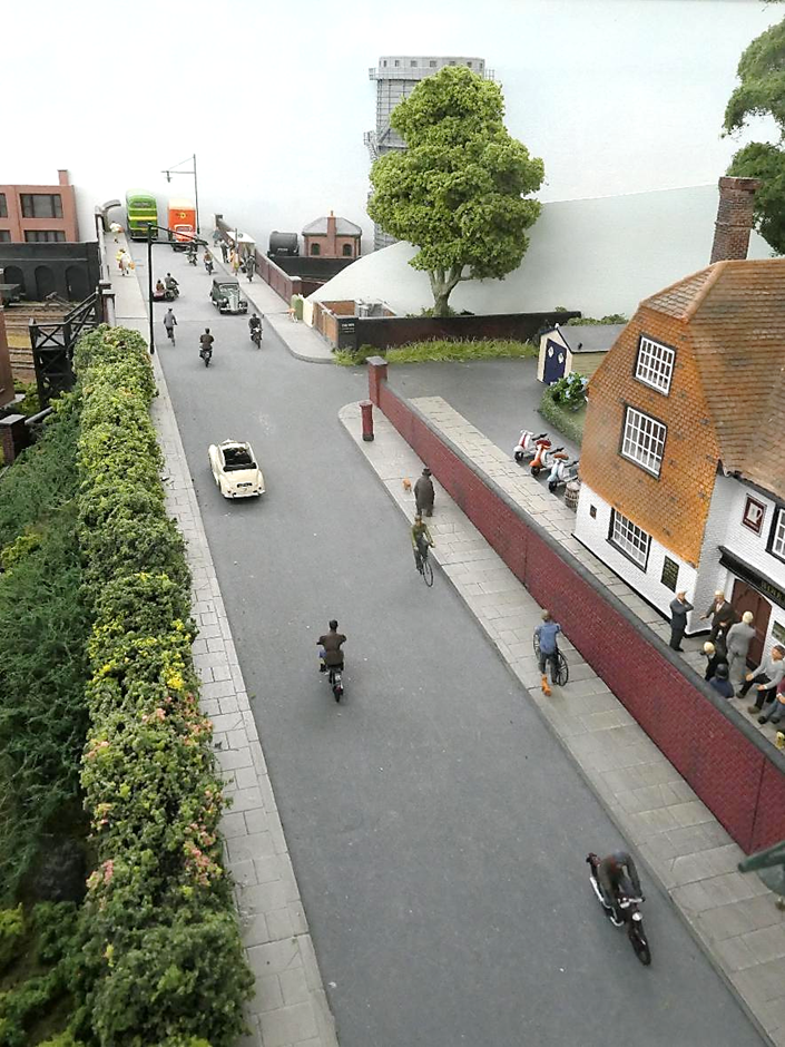 View along Somersbury Lane, thronging with pedestrians and traffic from this period including cyclists motorcycles and a motorcycle combination,.
This view cannot be seen by simply standing in front of the layout.
www.EwhurstGreen.com
