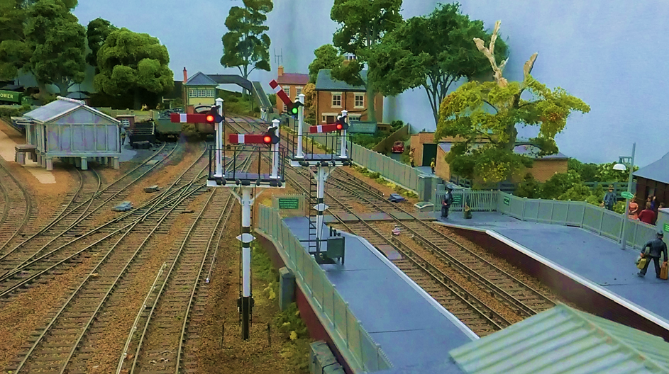 www.EwhurstGreen.com 

Two pairs of T-bracket signals for Platform 1 (left) and Platform 2 (right). The proceed aspect is for the Up Main (to Dorking) out of Platform 2.
Both bracket signals display Rule 55 exemption plates.

