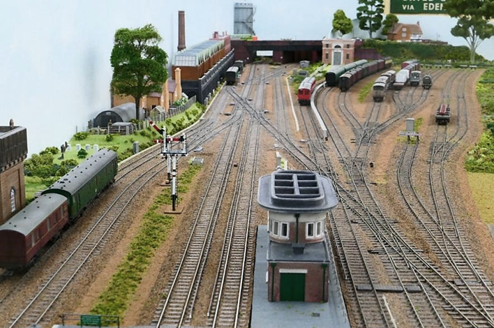 Looking south towards the double junction and the line to Cranleigh (curves away just to the left of and behind the sub-station) from above the Up Main Line platform.
The correct six-foot dimension between Up and Down Main lines is noticeable in this photograph as is the correct conductor rail offset whilst allowing for the 16.5mm gauge track.
www.EwhurstGreen.com